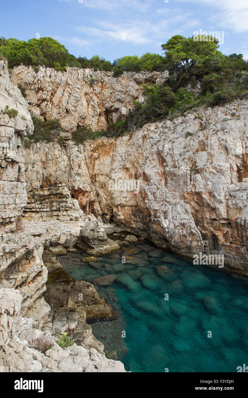 Empty sea cove, shallow water and steep and rugged cliff at the Lokrum Island in Croatia. Stock Photo