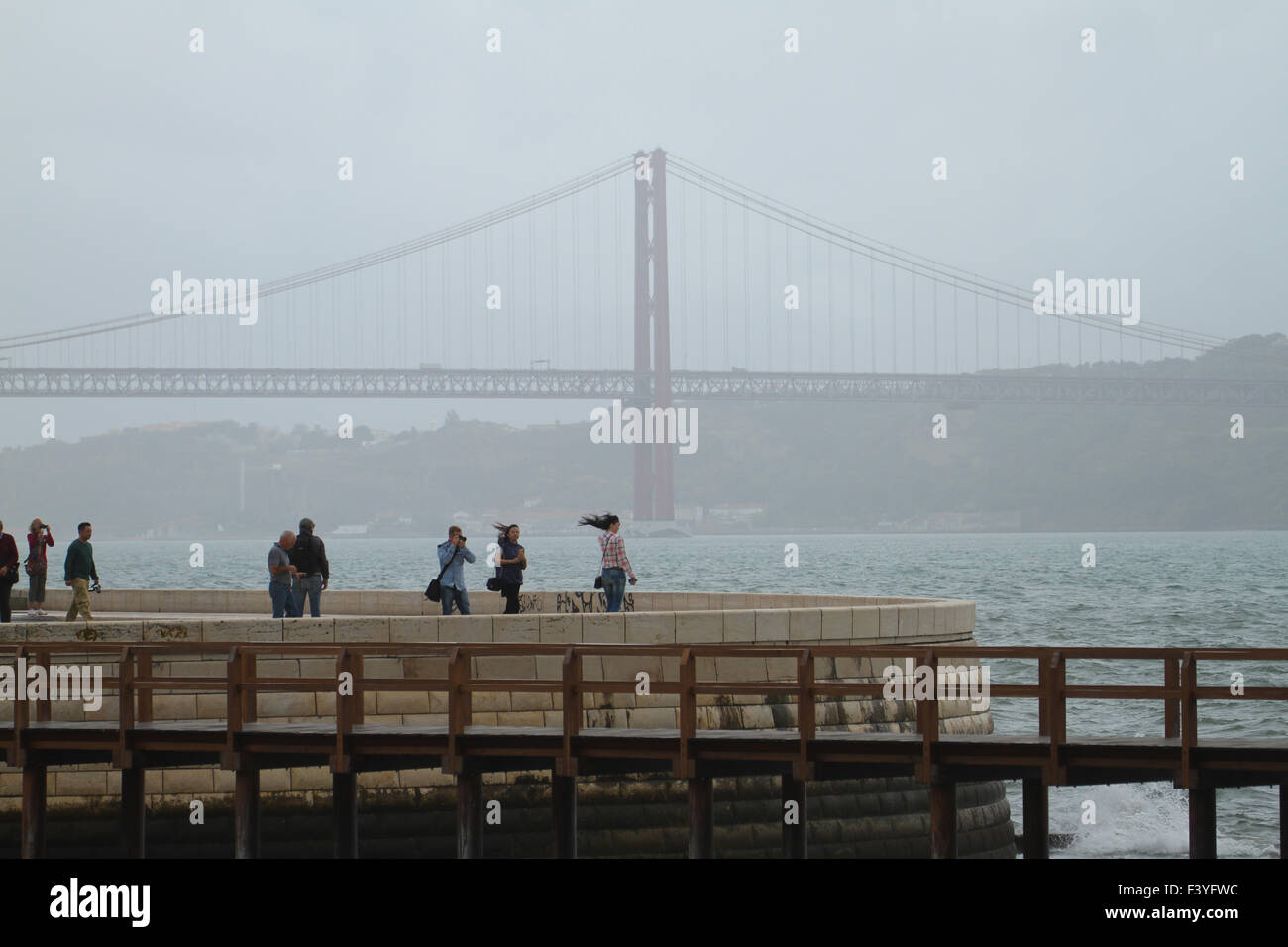 Lisbon, Portugal, 5 October, 2015. People seen by the north bank of Tegus river with a back drop of the 2km-long 25th of April Bridge. The suspension bridge links Lisbon with Almada was inaugurated on August 6, 1966. Credit: David Mbiyu/ Alamy Live News Stock Photo