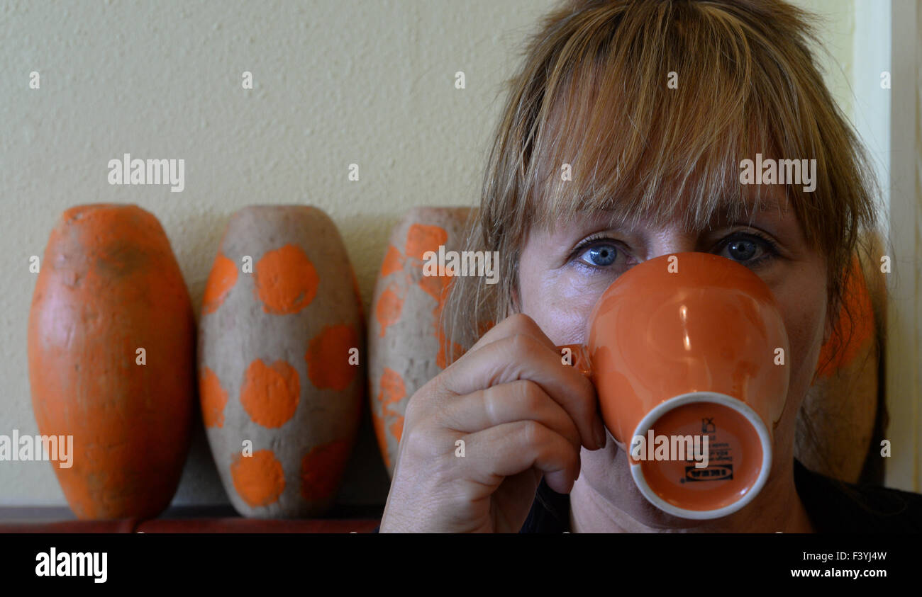 Woman with tussled hair drinking from an orange mug. Stock Photo