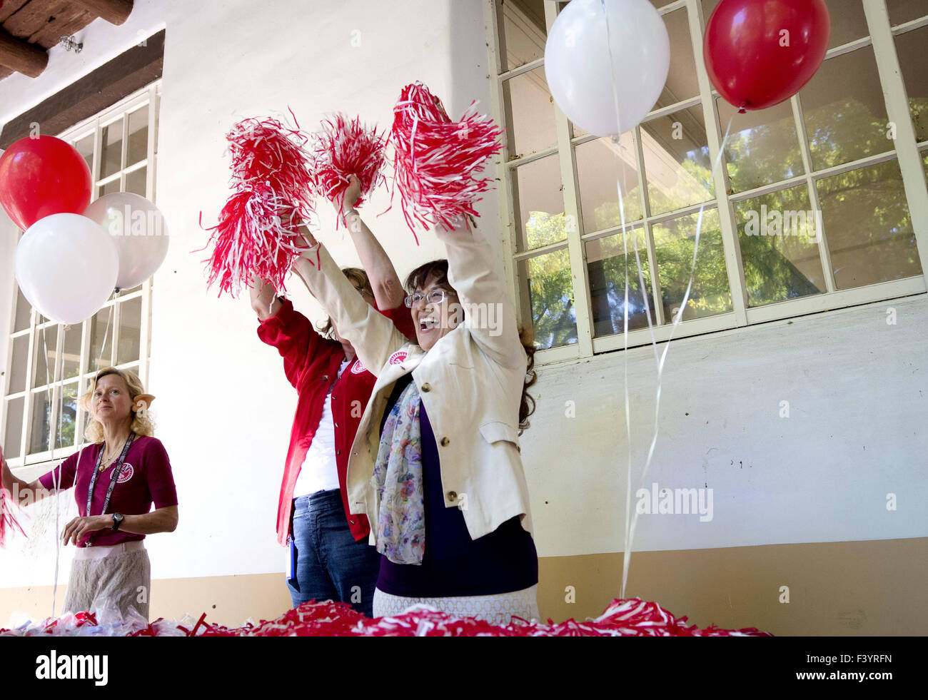 Albuquerque, NM, USA. 13th Oct, 2015. 101315.Gina Urias-Sandoval, right, staff counselor and director of the Executive MBA program at the University of New Mexico, cheers with Katherine Turner, second from right, a UNM staff council representative and a UNM alumni, during the Staff Council's annual homecoming luncheon in the Dominguez Plaza at UNM, Tuesday, Oct. 13, 2015, in Albuquerque, N.M. ''Everyone's a Lobo. Woof, woof, woof. Go staff, '' cheered Urias-Sandoval and Turner while handing out pompoms and cookies. Lobo will take on Hawaii Rainbow Warriors in Saturday's Homecoming game. (Cred Stock Photo