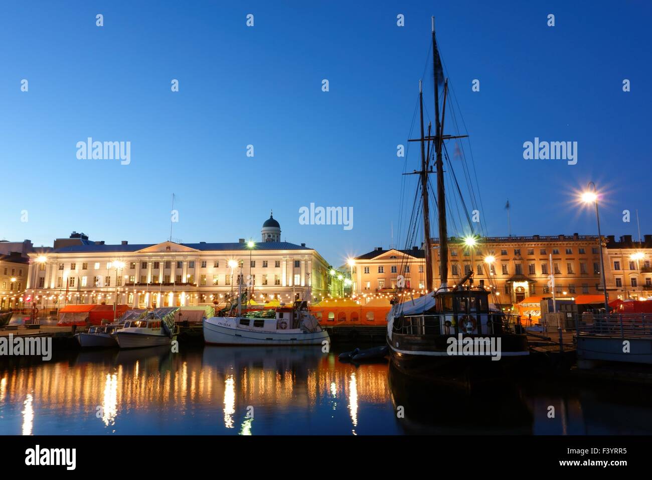 Herring fishing boats and a sailing ship at the Helsinki Market Square on early October evening during annual Helsinki Baltic Herring Fair. Stock Photo