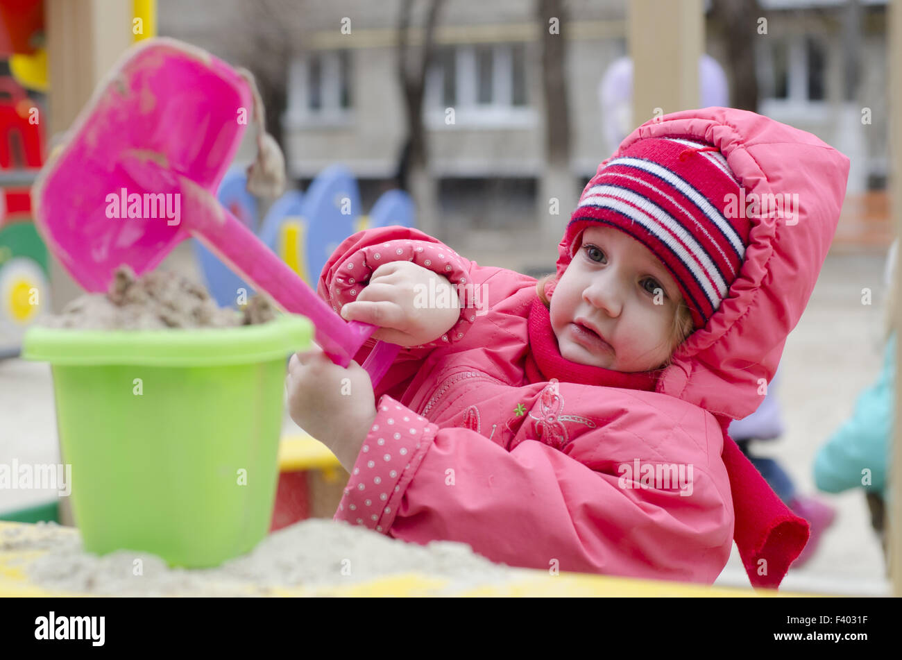 little girl pours sand bucket in sandbox Stock Photo