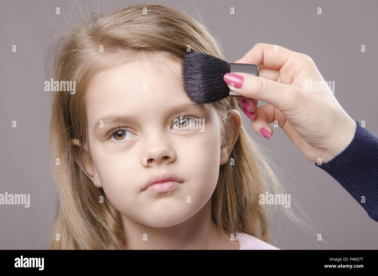 Makeup artist deals powder on face of girl Stock Photo