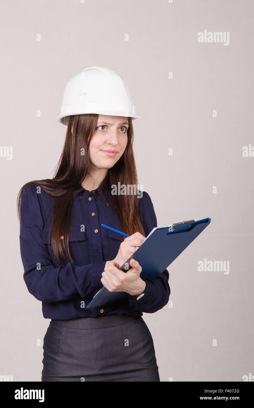 Girl a helmet writes in pencil folder Stock Photo - Alamy