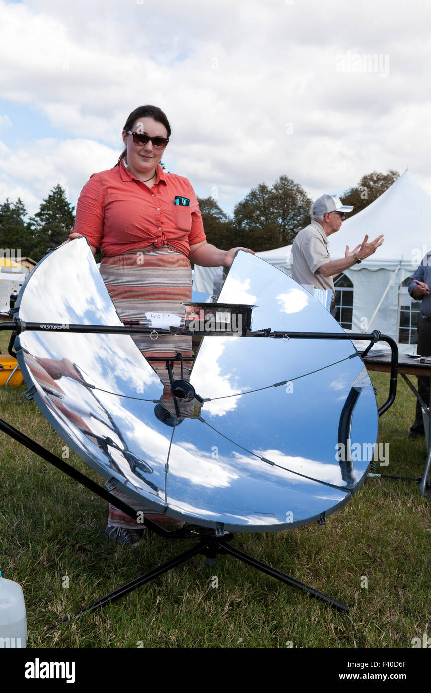 Woman demonstrating a parabolic solar cooker - USA Stock Photo