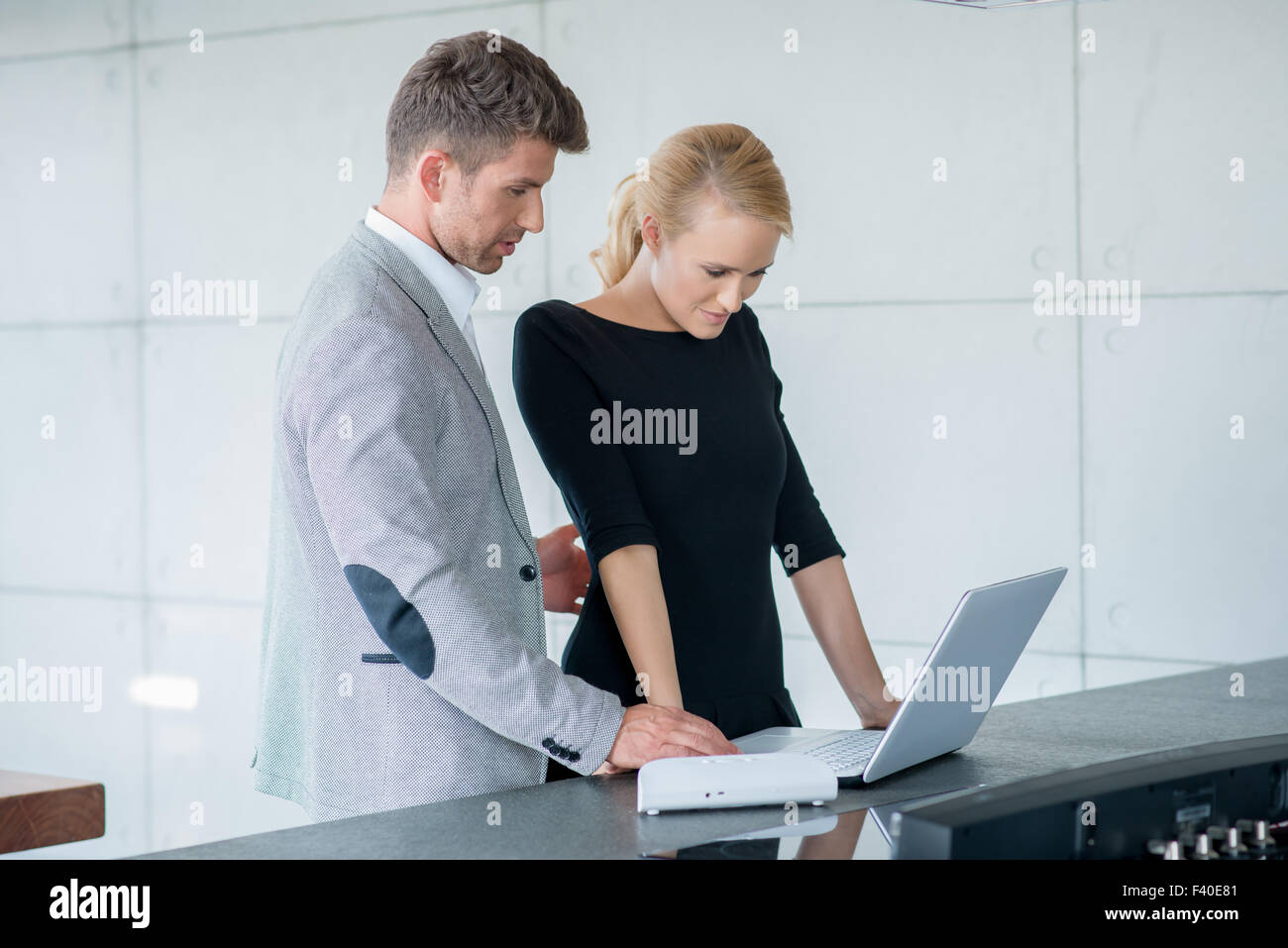 Professional Couple Looking Down at Laptop Stock Photo