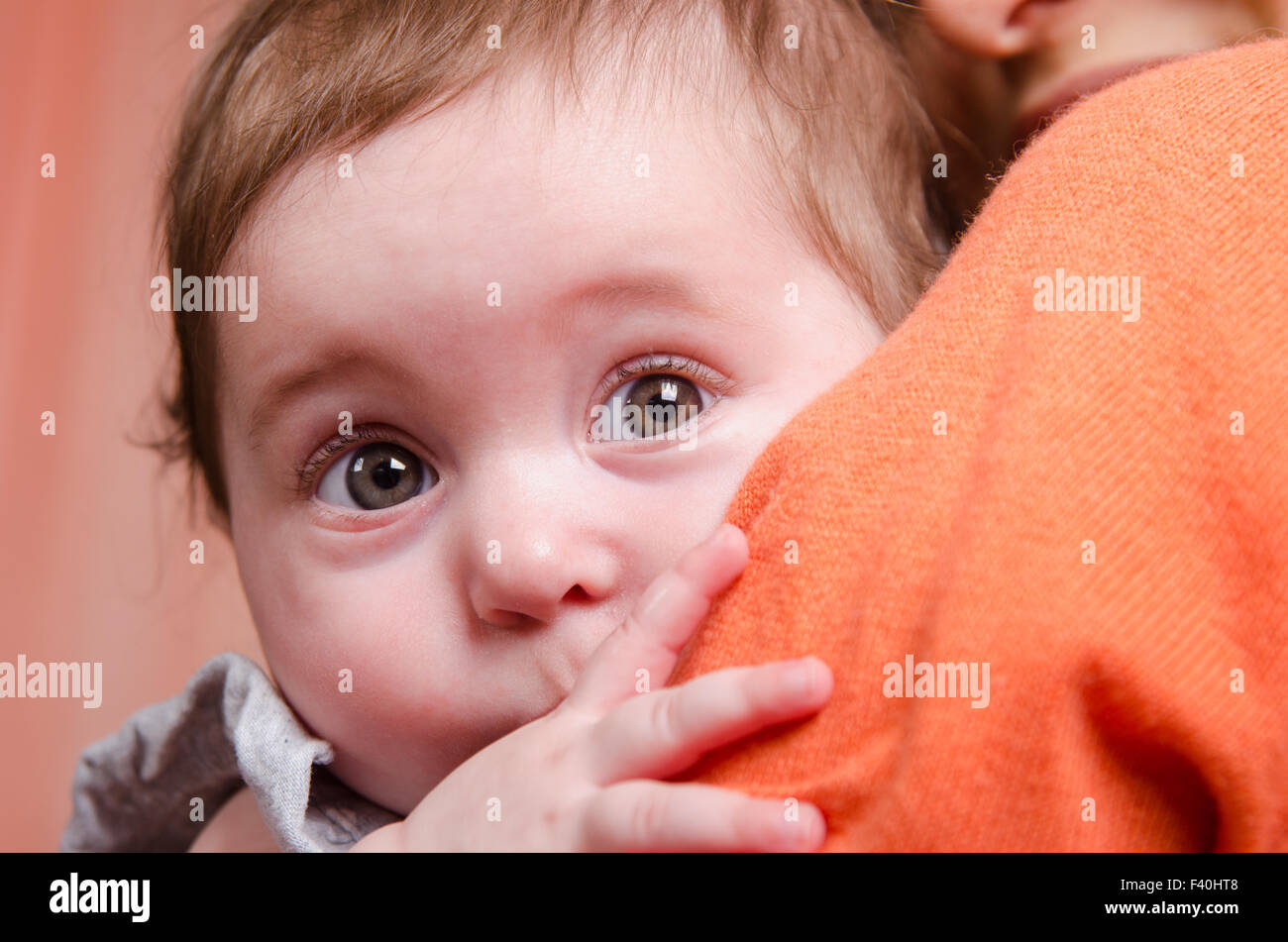 Scared kid hiding behind mom's shoulder Stock Photo