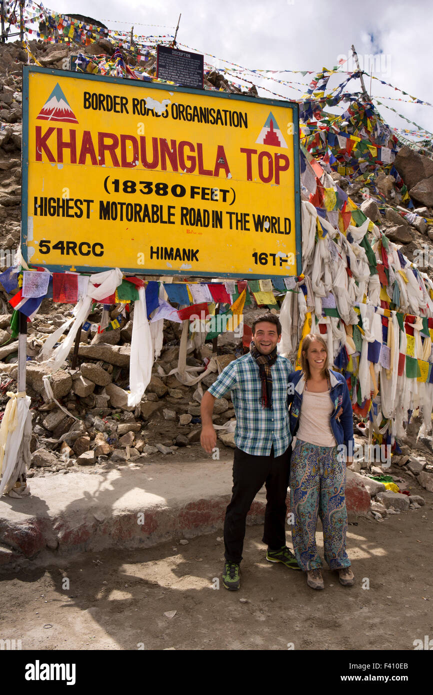 India, Jammu & Kashmir, Ladakh, Leh, Khardung La Pass top, foreign tourists and Buddhist prayer flags at summit sign Stock Photo