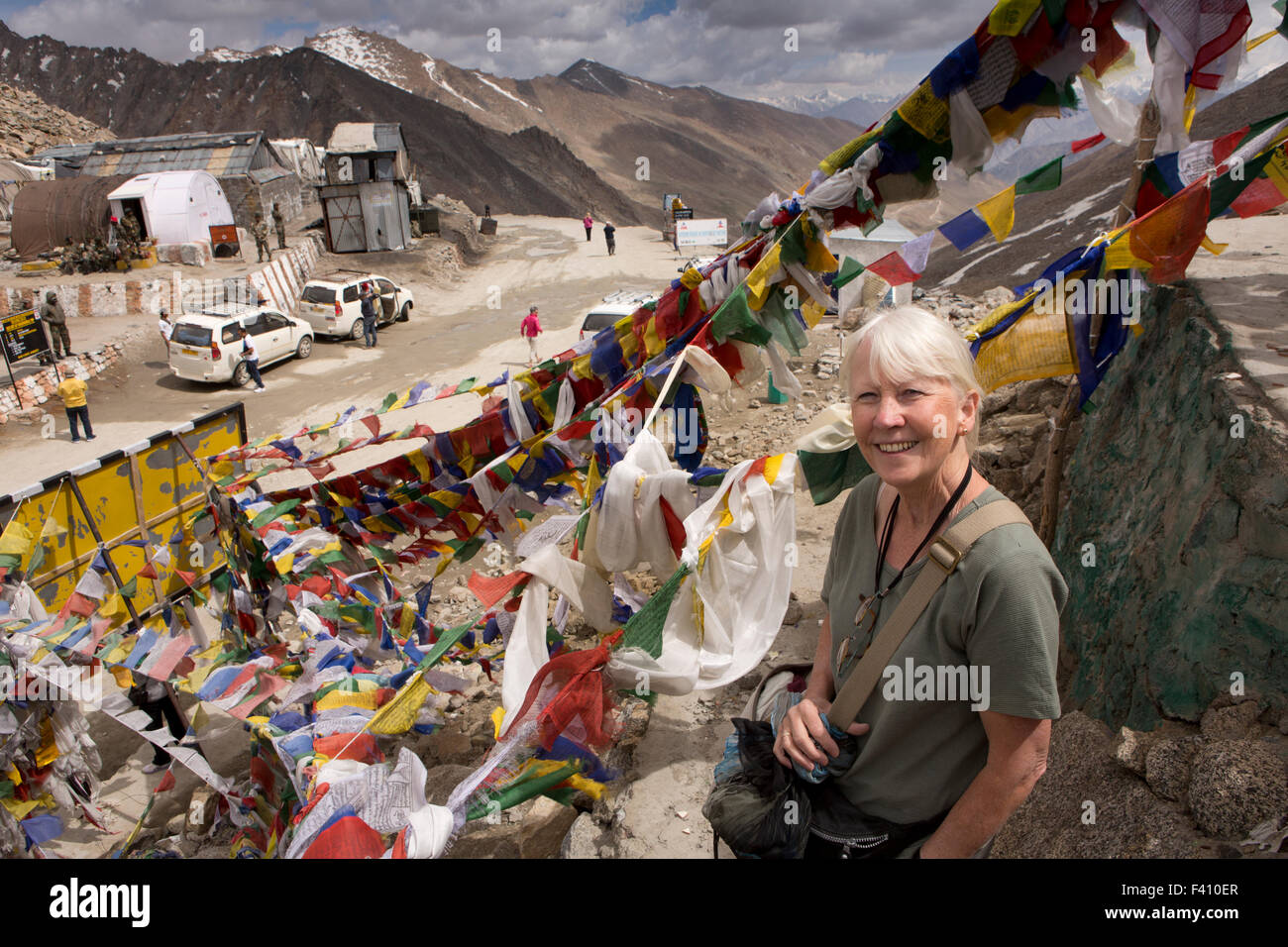 India, Jammu & Kashmir, Ladakh, Leh, Khardung La Pass top, tourist amongst Buddhist prayer flags at summit Stock Photo