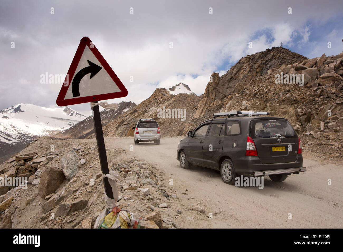 India, Jammu & Kashmir, Ladakh, Leh, Khardung La, bend warning sign and cars on world’s highest motorable road Stock Photo