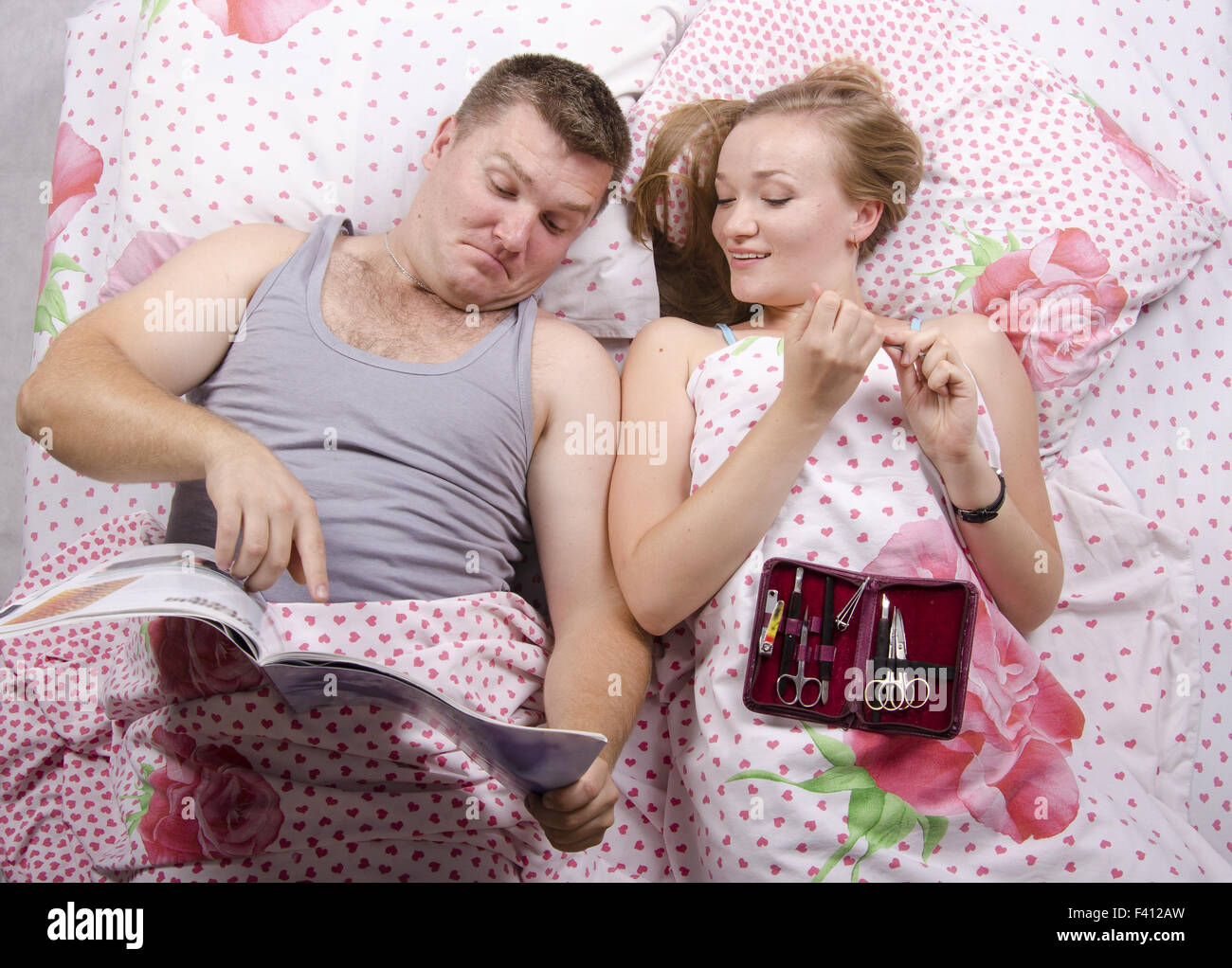 Husband with magazine, wife manicure set Stock Photo