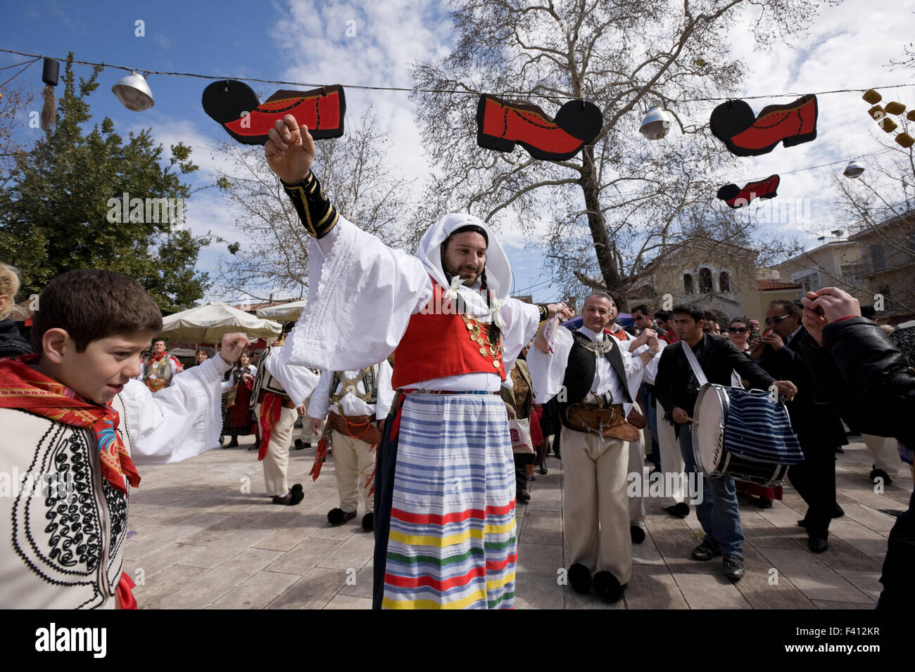 Vlach bride escorted by a vlach captain, dancing in Thebes square, decorated by hung red dummy tsarouhia shoes overhead. Greek Dionysian mysteries. GR Stock Photo