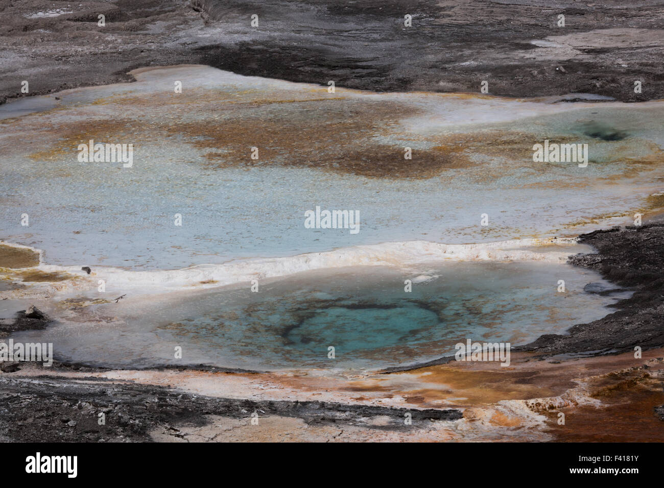 A volcanic pool of hot aqua blue water and rust colored surroundings at ...