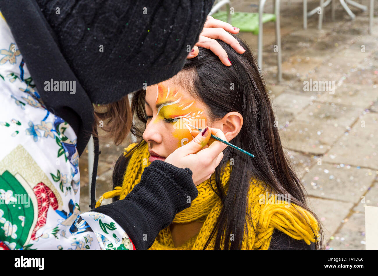 At Carnevale a young woman is getting a face painting Stock Photo