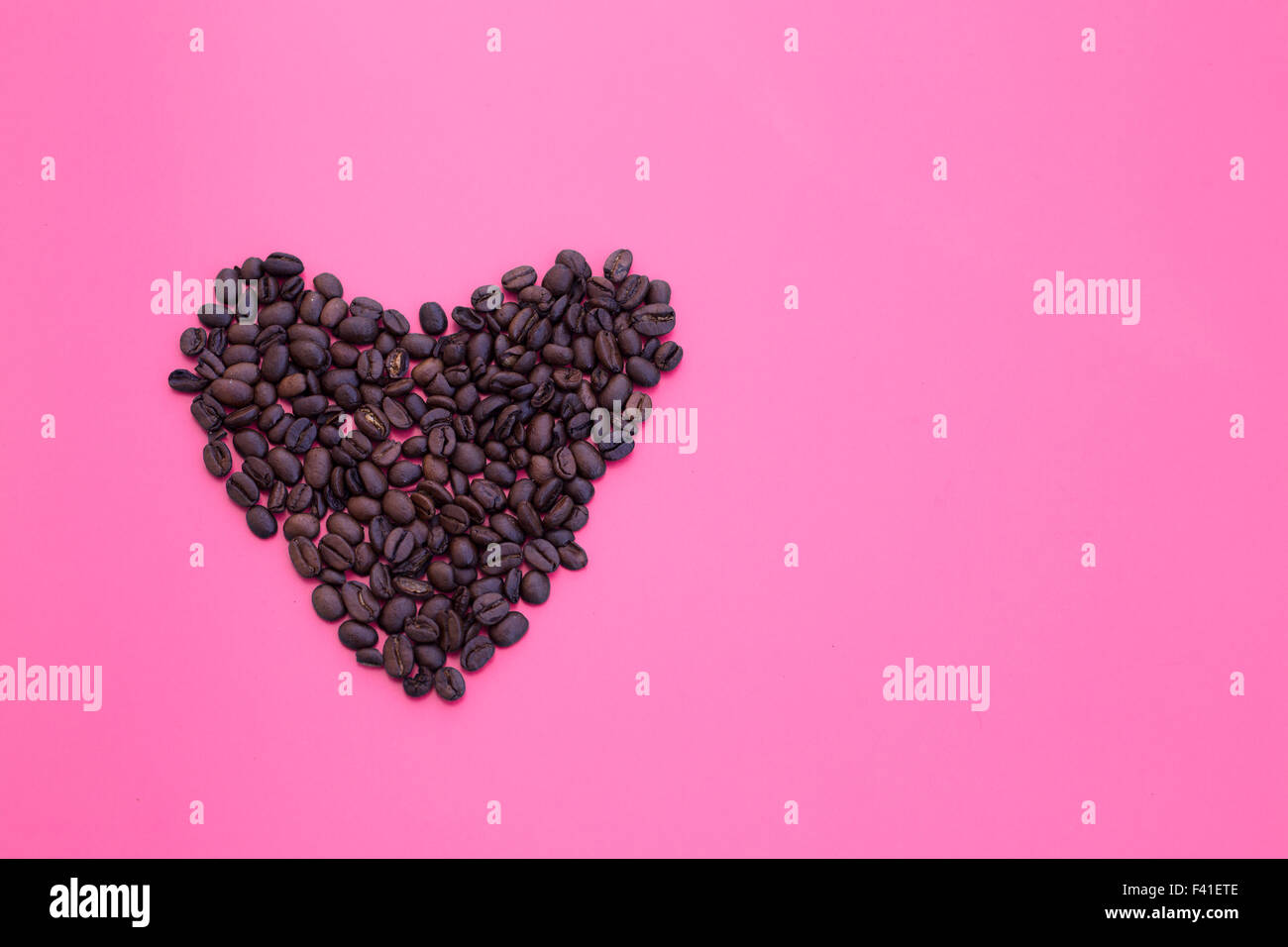 heart shape of coffee beans on pink background Stock Photo