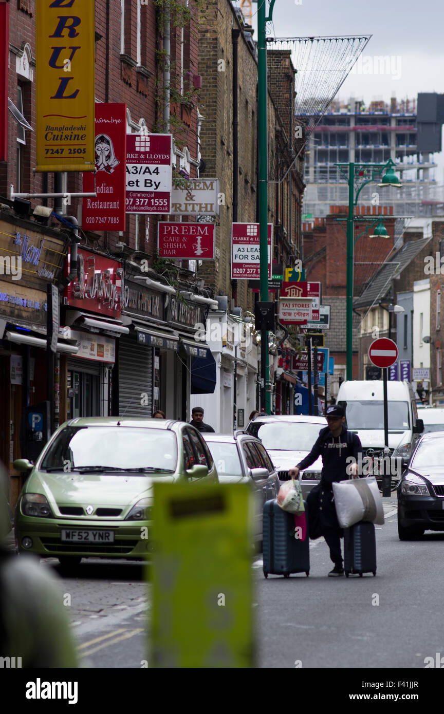 Pedestrians passing a few curry restaurants on Brick Lane in East London Stock Photo