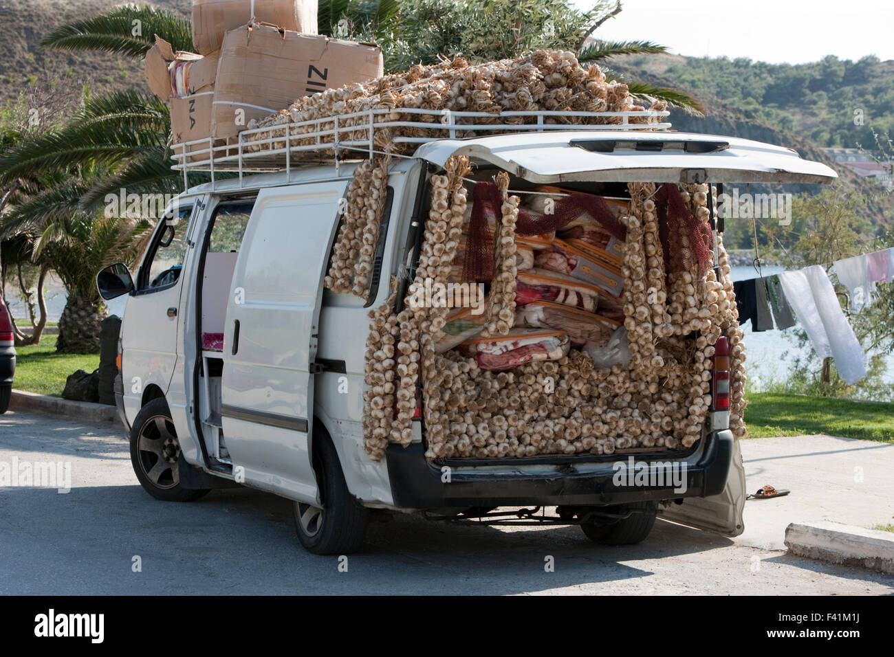 Pile of dried hanging garlic cloves for sale among packs of blankets on a  gypsy peddler's van park on the street Stock Photo - Alamy