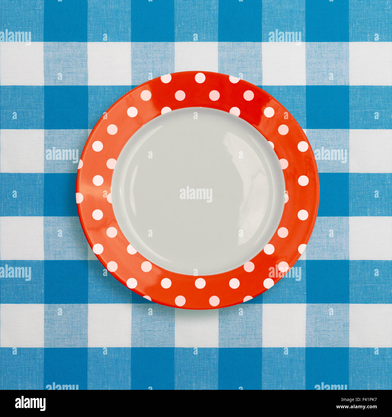 Polka dot red white dinner plate on blue checked tablecloth Stock Photo