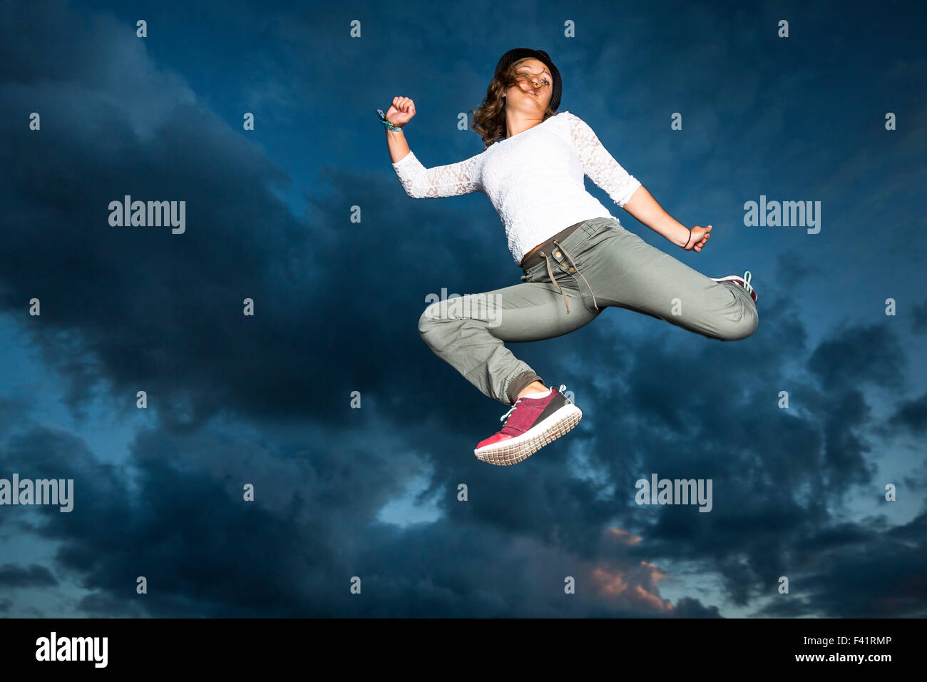 Young woman, 19 years old, jumping, in mid-air, against the evening sky Stock Photo