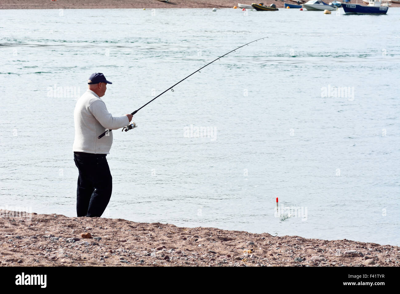 Man sea fishing off the back beach on a hot sunny September day in  Teignmouth, Devon, England Stock Photo - Alamy