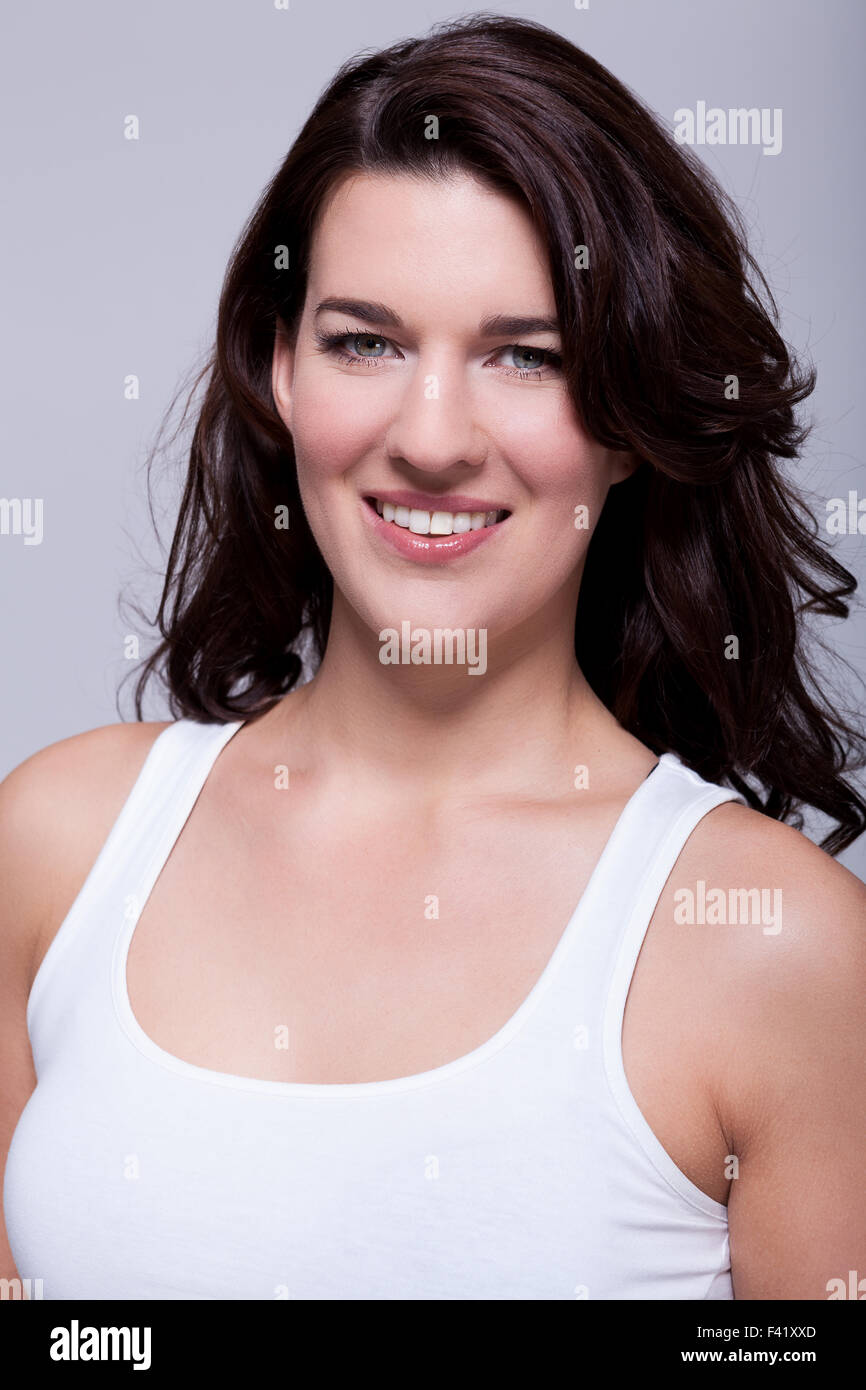 Smiling attractive woman with a lovely warm friendly smile and shoulder ...