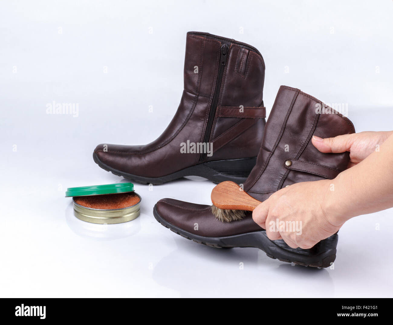 woman's hand polishing boot with shoe brush on white background Stock Photo