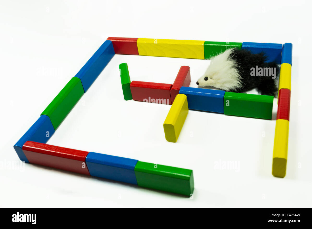 Maze constructed from wooden painted pieces and toy mouse trapped in one corner , isolated on white Stock Photo