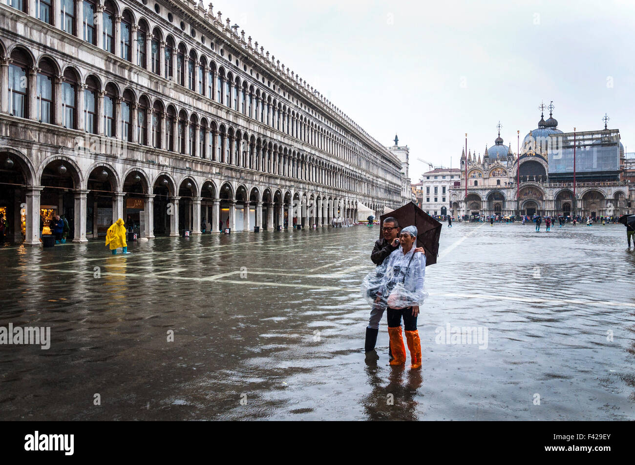 St Marks Square, Venice, Italy. 14th October 2015. A couple of tourists in Piazza San Marco pose for a photo during Acqua alta or 'high water' the exceptional tide peaks that occur periodically in the northern Adriatic Sea. Photo by: Credit:  Richard Wayman/Alamy Live News Stock Photo