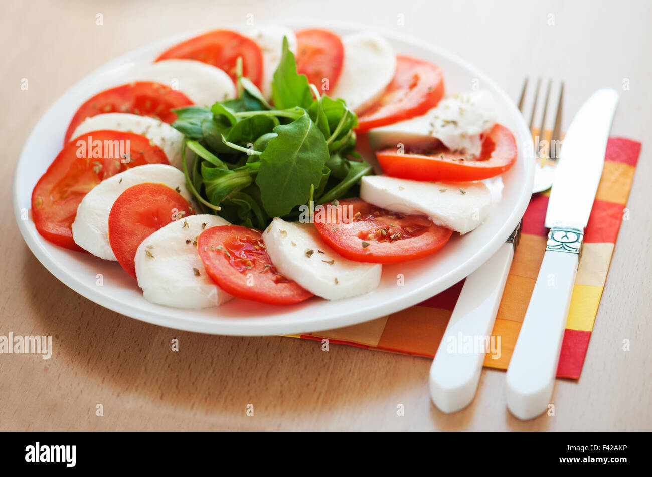 Italian salad with tomatoes and mozzarella with a fork and knife Stock Photo