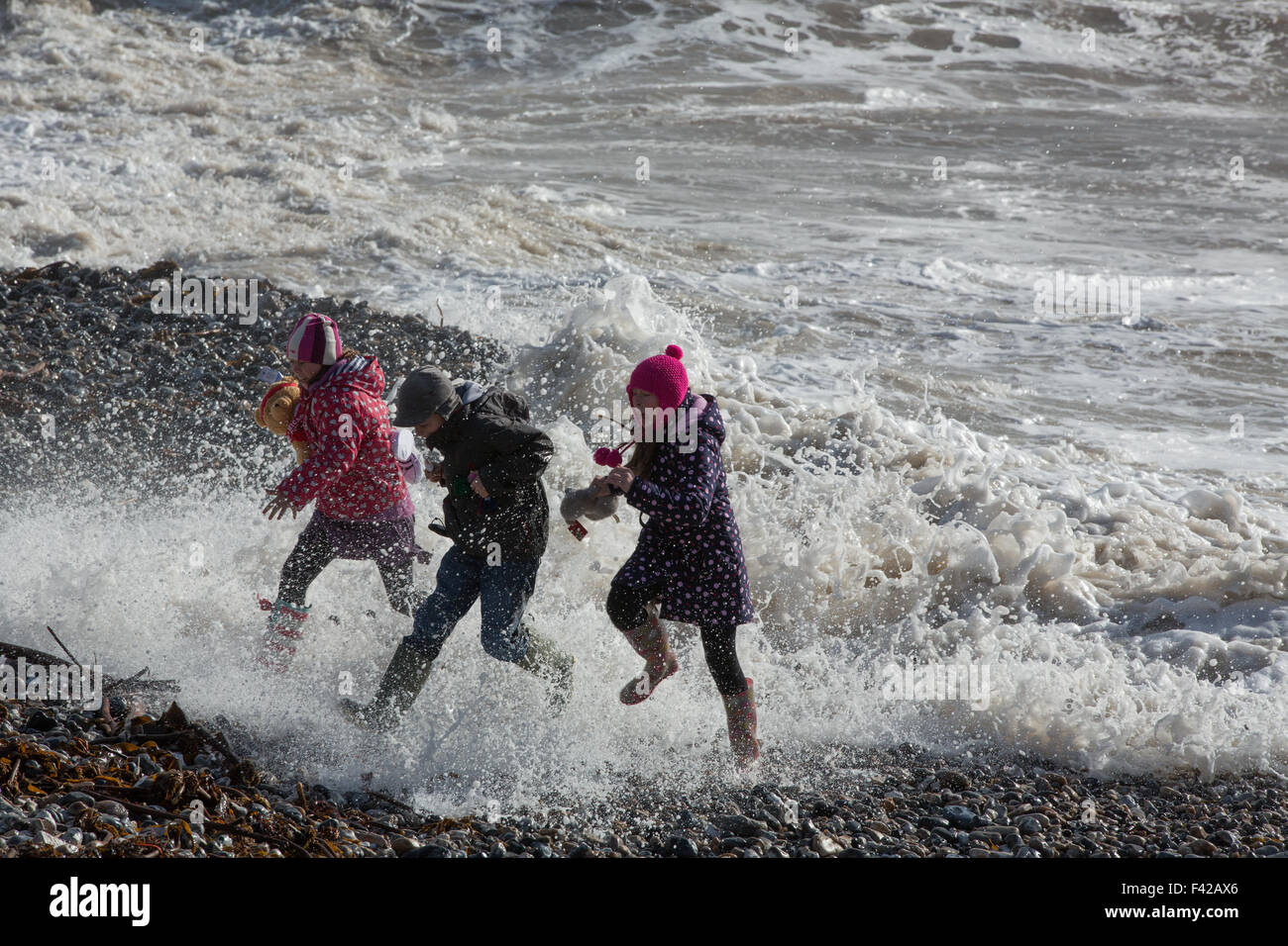 children escaping surf; storm waves breaking over the Cobb at Lyme Regis, Jurassic Coast, Dorset, England, UK Stock Photo