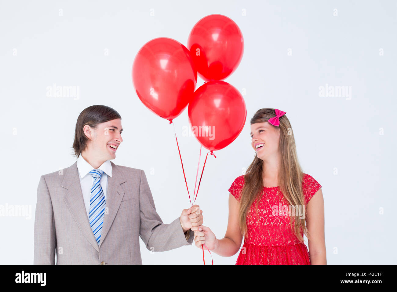 Smiling geeky couple holding red balloons Stock Photo - Alamy