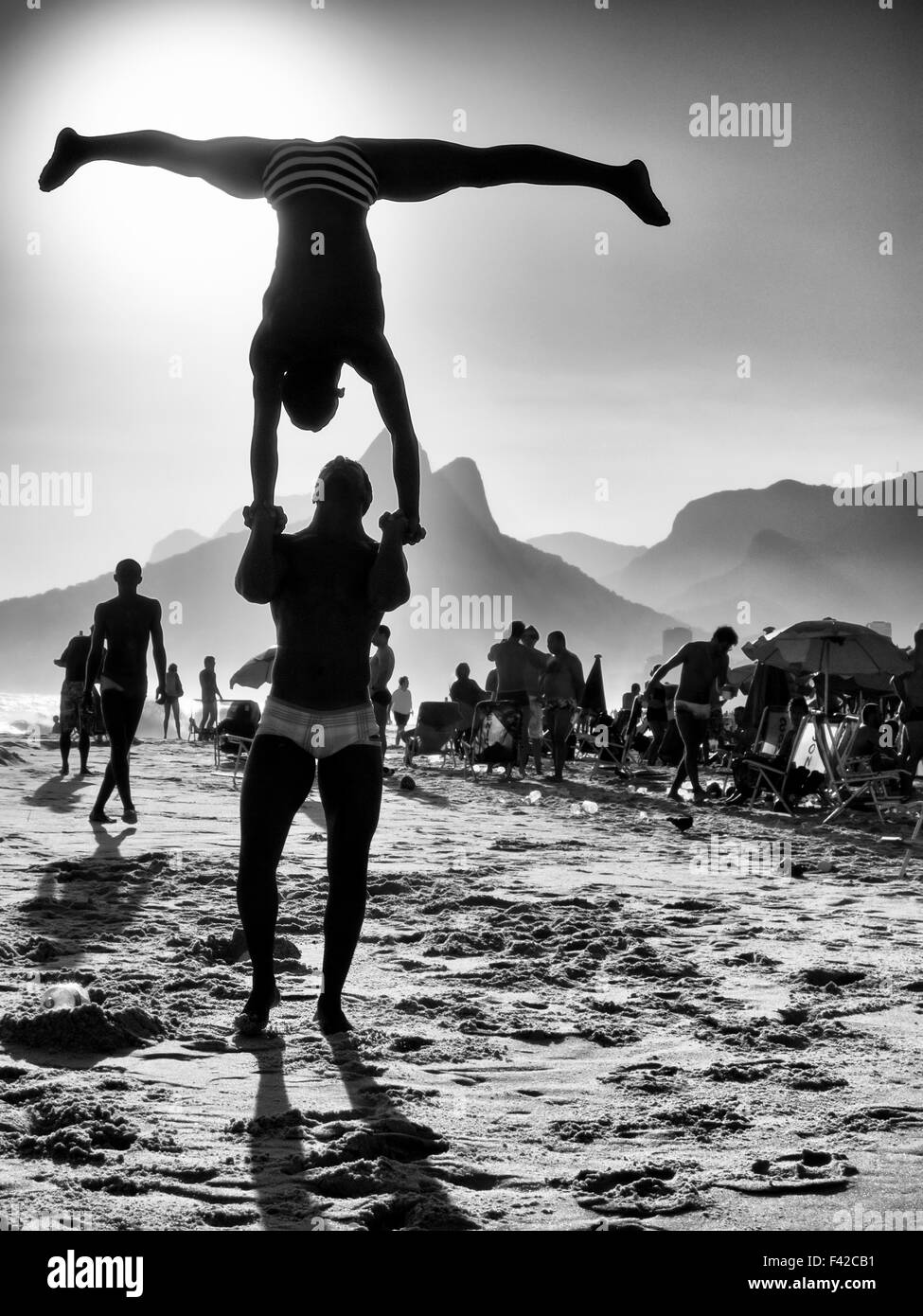 Silhouettes making acrobatic poses in front of a black and white sunset beach scene at Ipanema Beach Rio de Janeiro Brazil Stock Photo