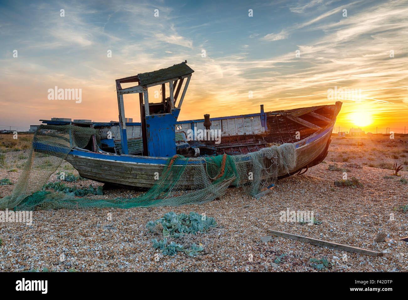 Stunning sunset over an old wooden fishing boat on the beach at Dungeness on the Kent coast Stock Photo