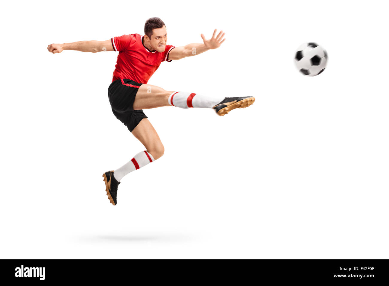 Studio shot of a male football professional kicking a ball in mid-air isolated on white background Stock Photo