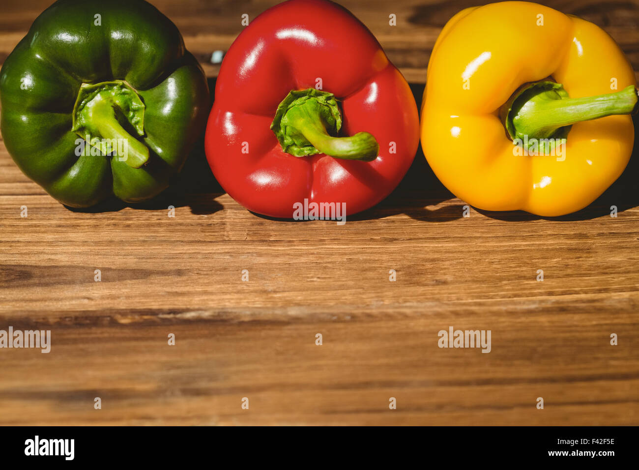 Three peppers on chopping board Stock Photo - Alamy