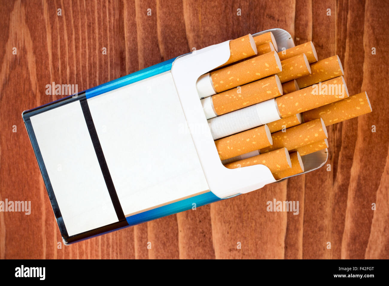 Open pack of cigarettes with the filter on brown table Stock Photo