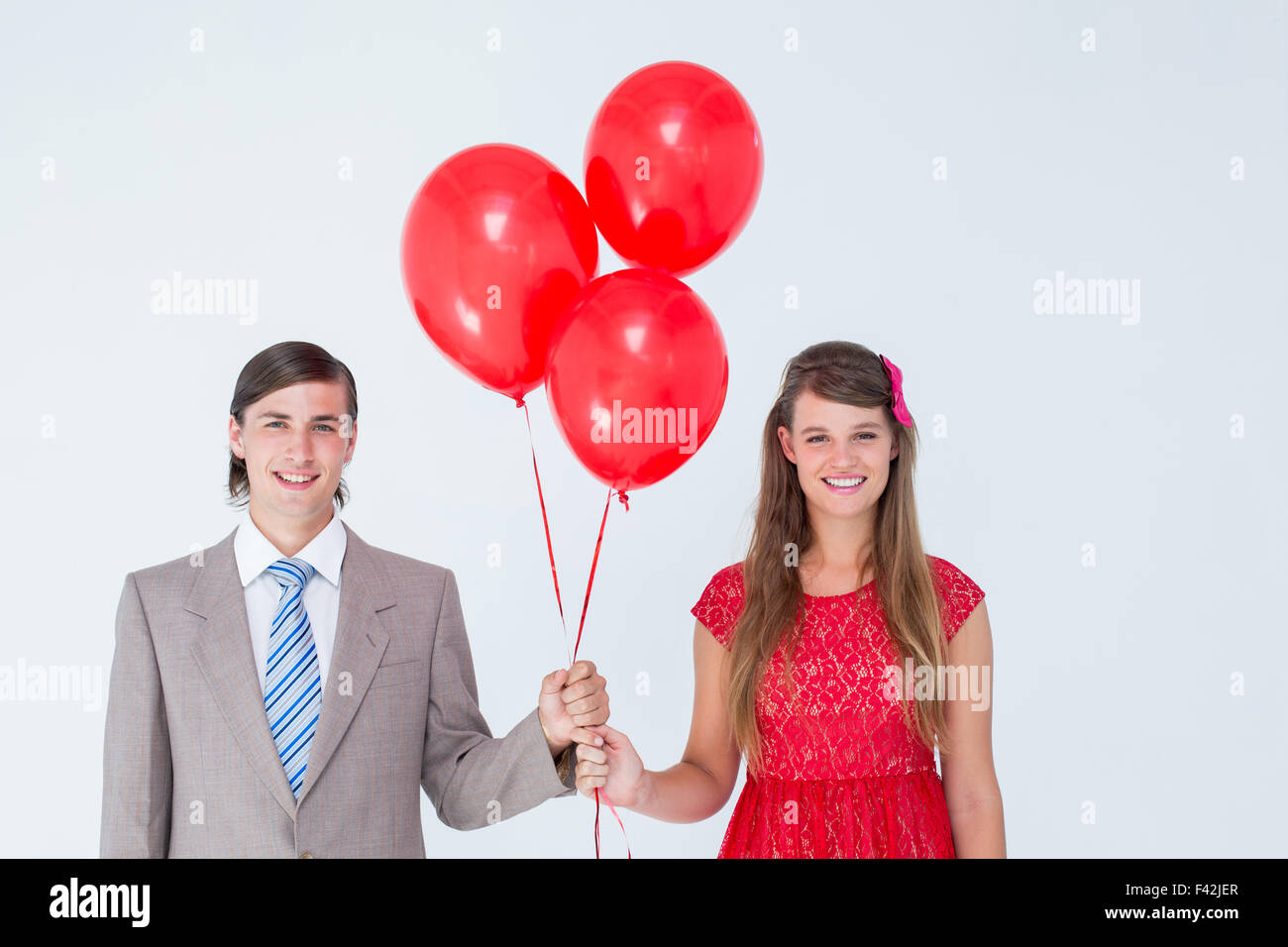 Smiling geeky couple holding red balloons Stock Photo - Alamy