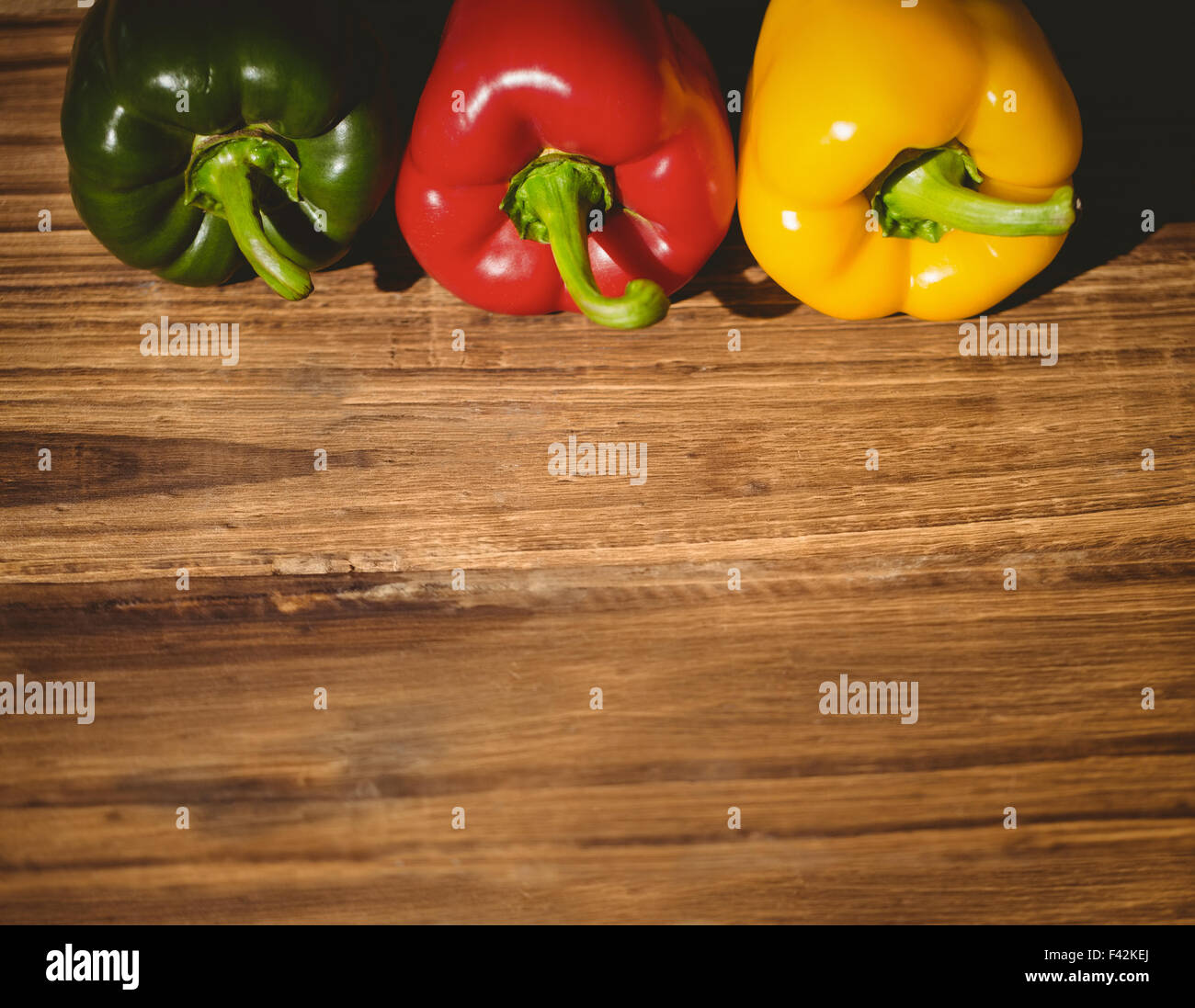 Three peppers on chopping board Stock Photo - Alamy