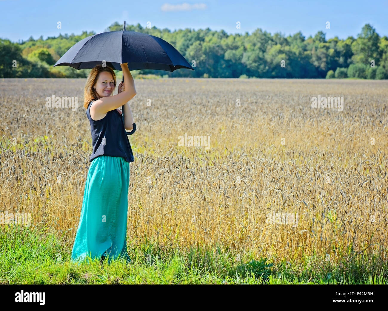Portrait of woman with umbrella in field Stock Photo