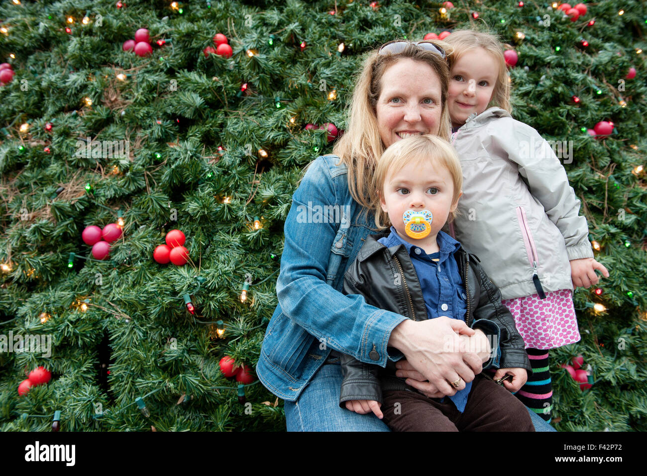 Mother and children posing in front of outdoor Christmas tree, portrait Stock Photo