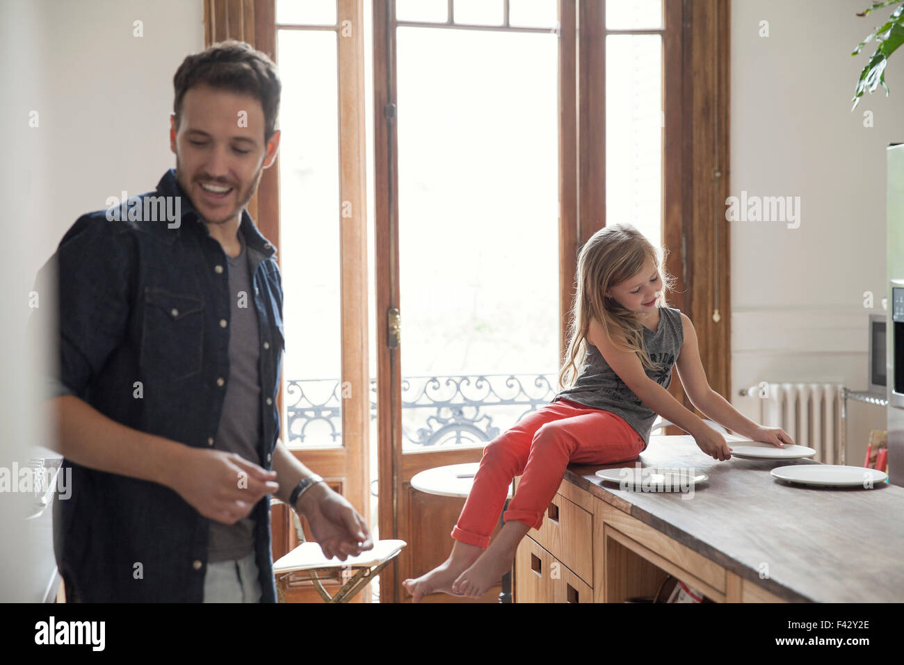 Girl helping father set table for family meal Stock Photo