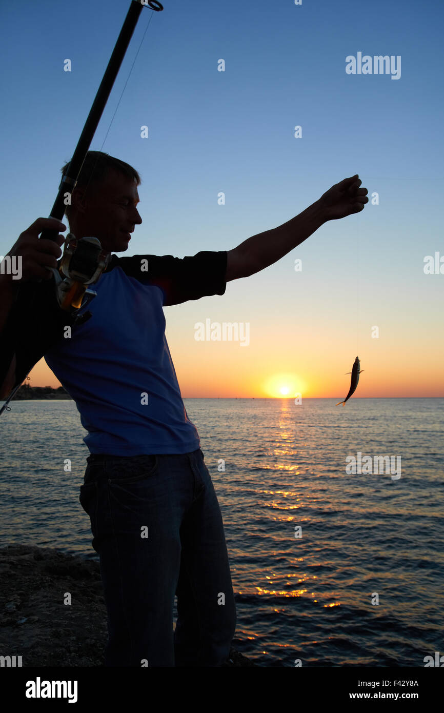 Fisherman fishes at the sunset Stock Photo - Alamy