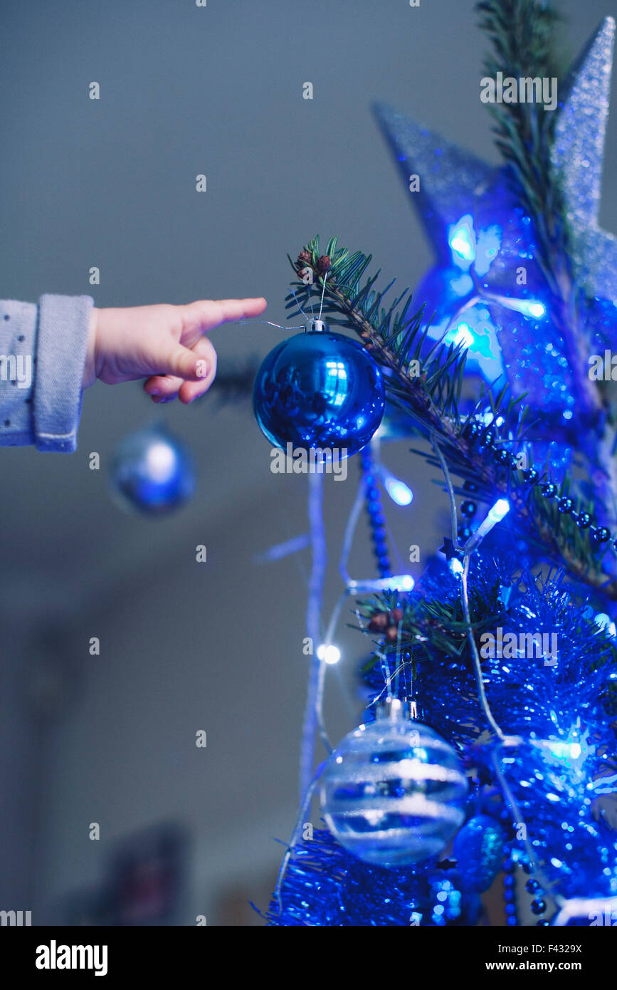 Baby reaching for Christmas tree ornament Stock Photo