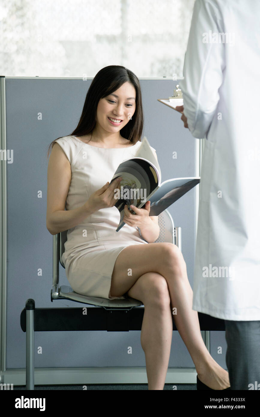 Woman reading magazing in medical waiting room Stock Photo