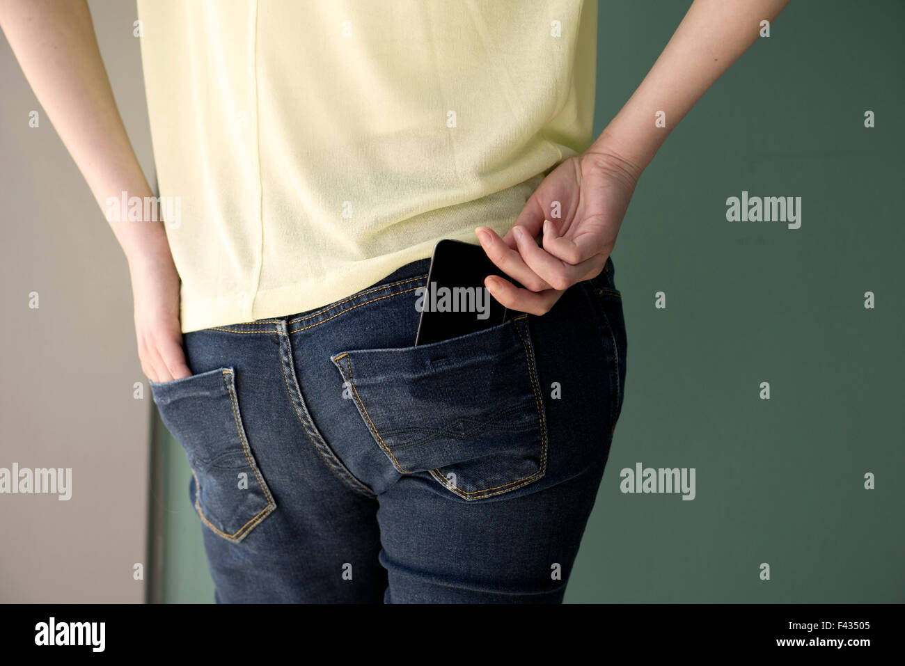 Woman placing cell phone in back pocket Stock Photo