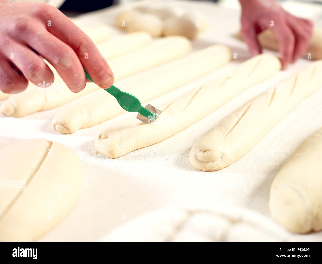 Baker scoring bread dough, cropped Stock Photo