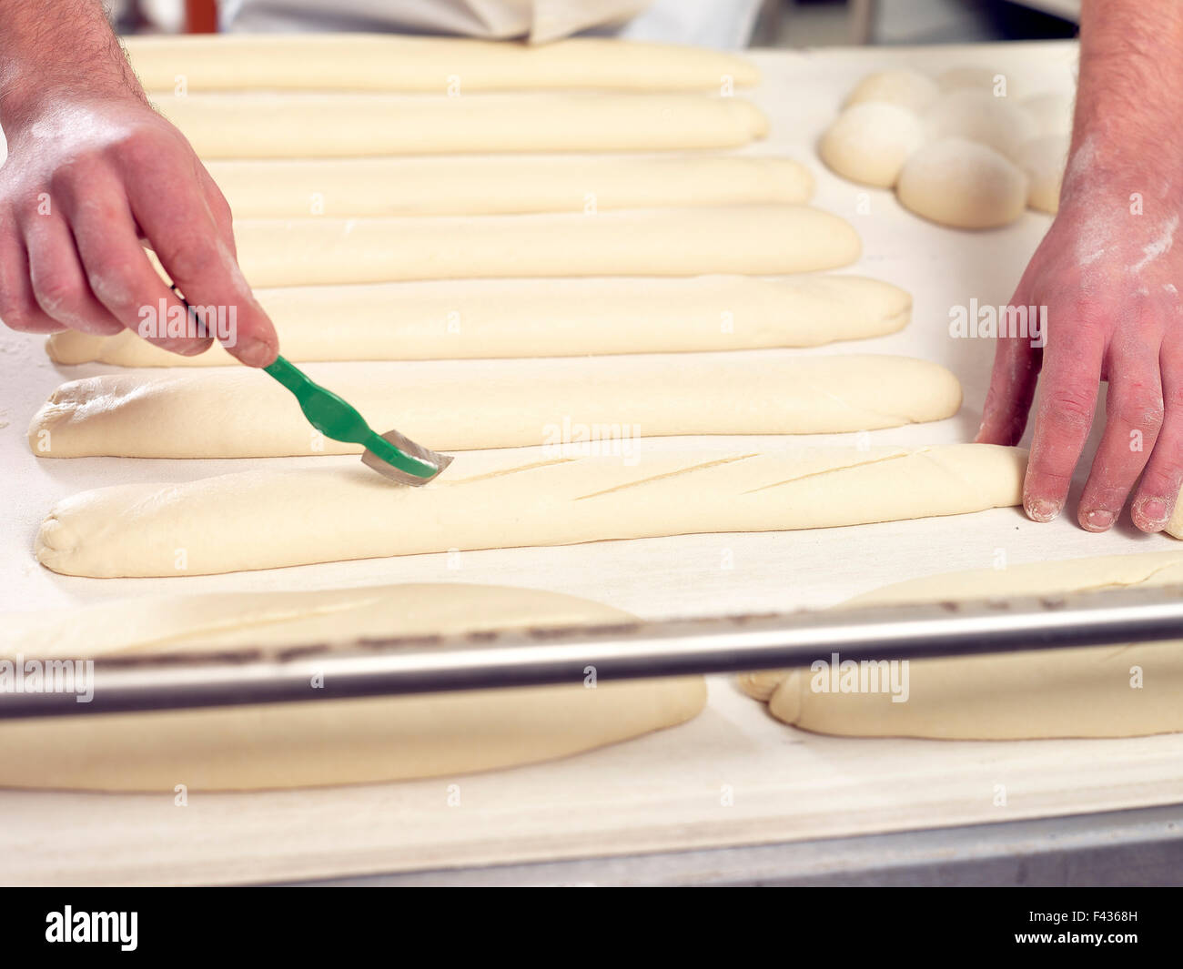 Baker scoring bread dough, cropped Stock Photo