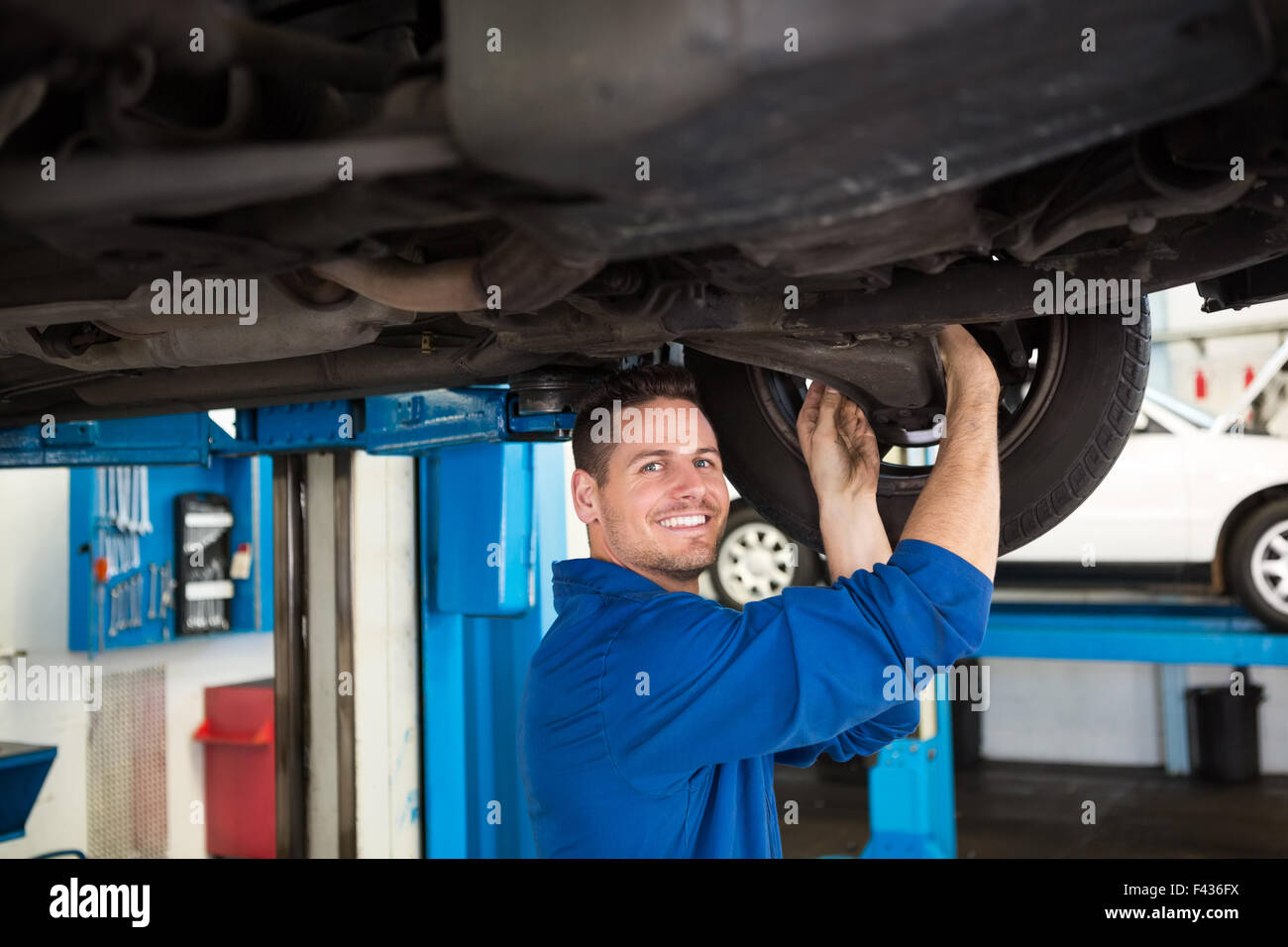 Smiling mechanic adjusting the tire wheel Stock Photo - Alamy