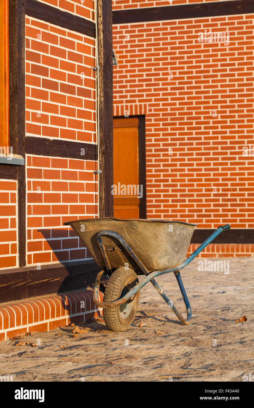 used wheelbarrow and renovated old buildnig Stock Photo Alamy