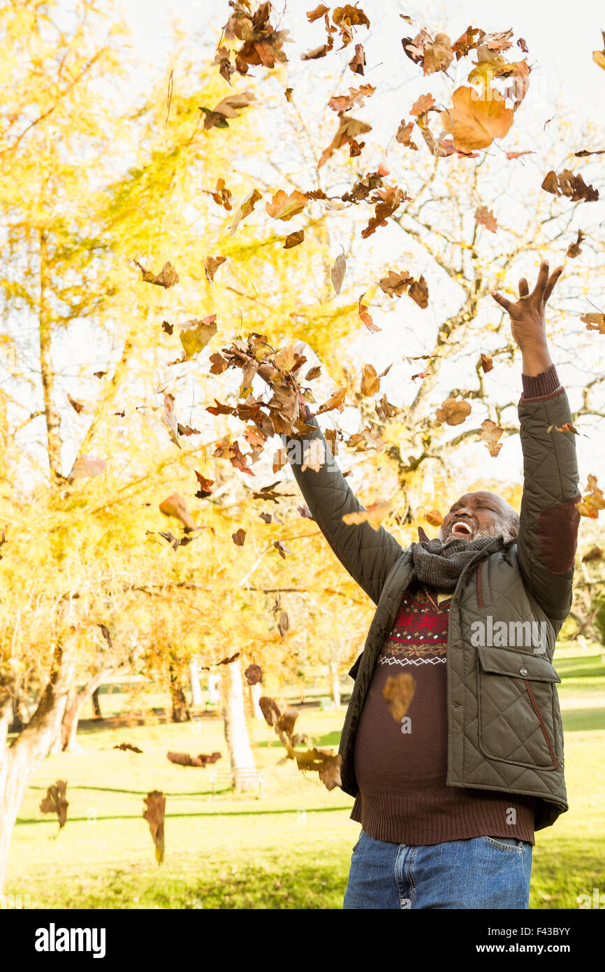 Happy old man throwing leaves around Stock Photo
